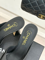 Black Chanel mules close-up showing gold CHANEL branding on insoles