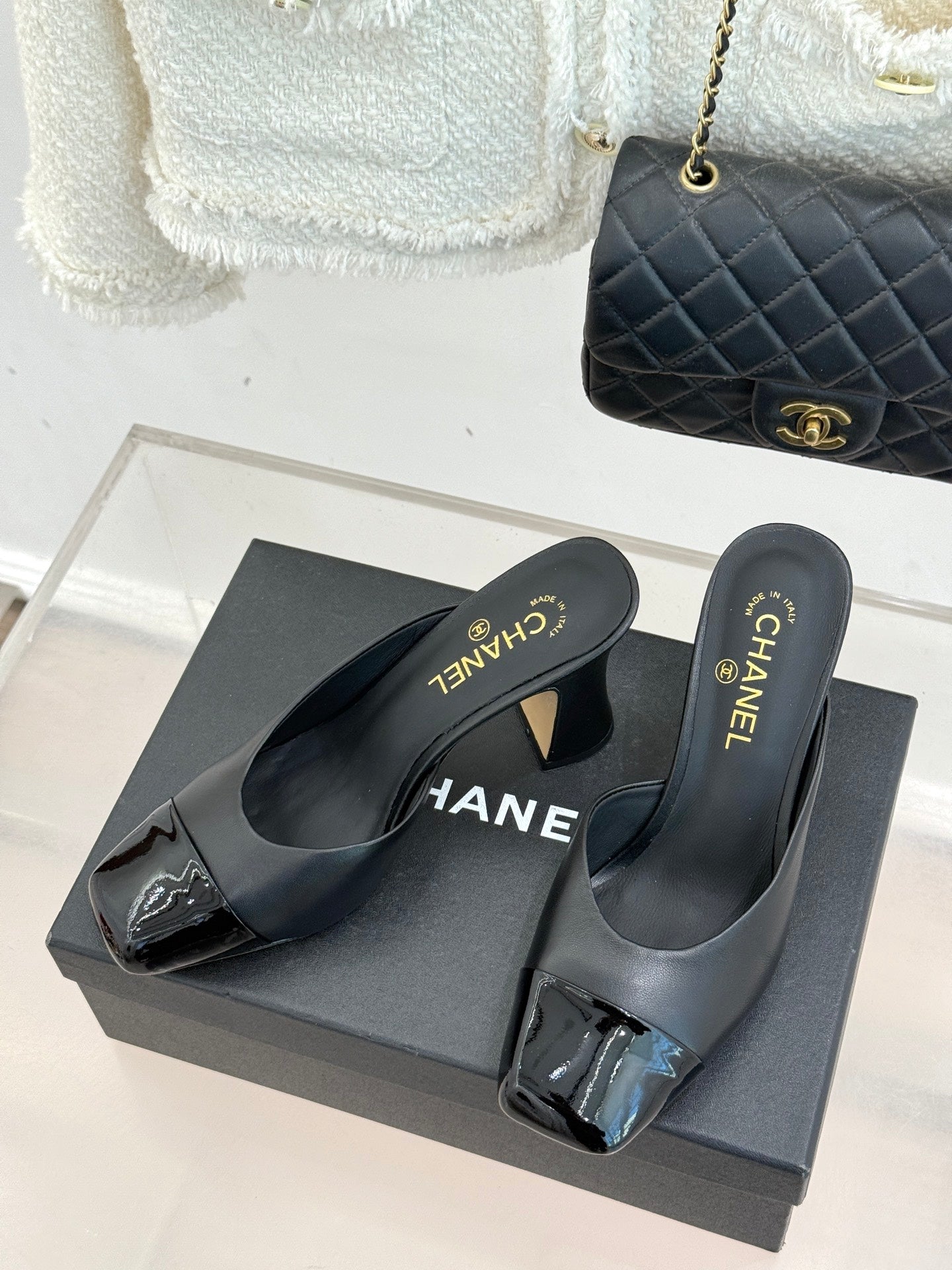 Black Chanel slip-on mules with gold logo and patent toe accents