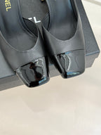 Close-up of black Chanel mules with glossy patent toe panels