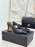 Black Chanel heeled mules with gold logo strap and glossy toe detail