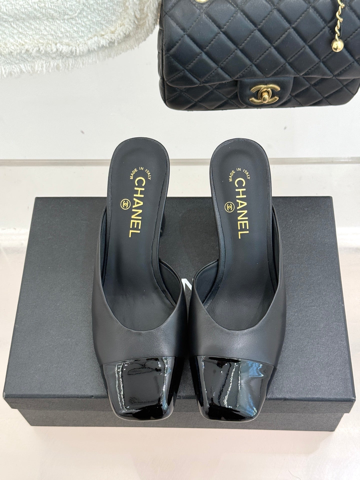 Pair of black Chanel heeled mules on a box with gold logo insoles