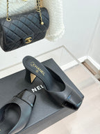 Black Chanel mules with open-toe cutout, gold logo front strap