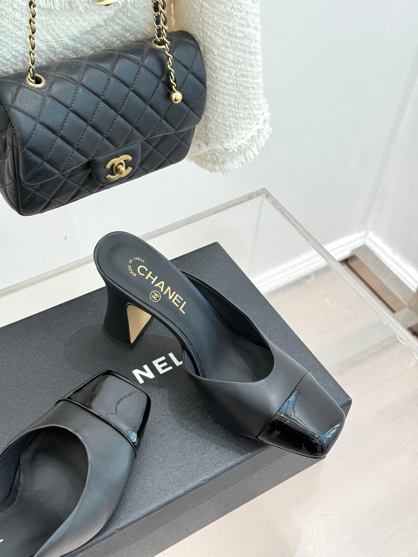 Black Chanel mules with open-toe cutout, gold logo front strap