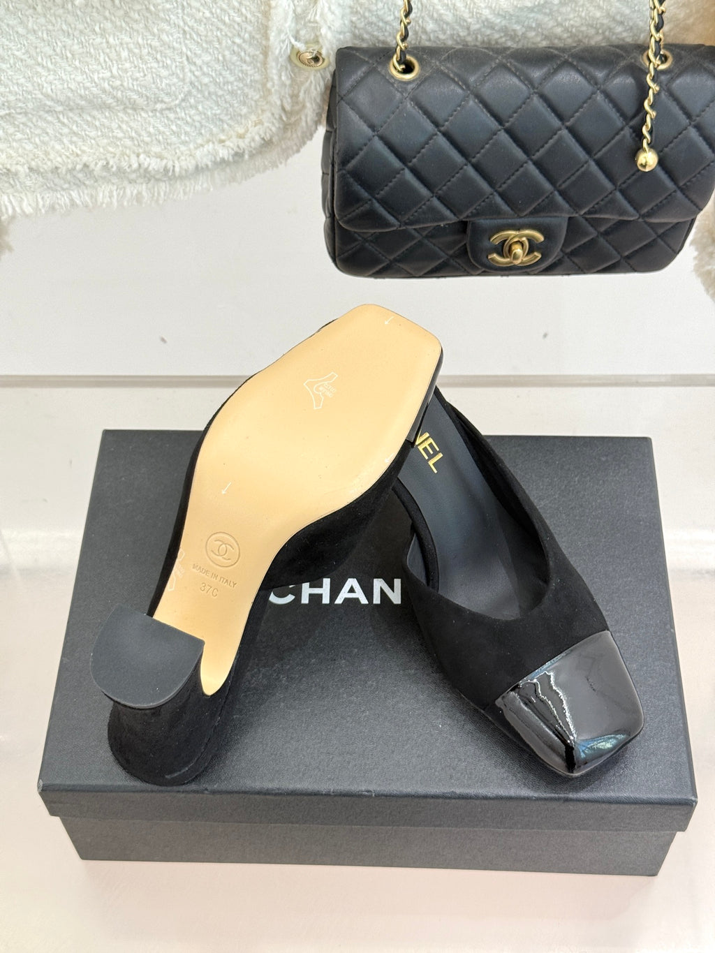 Black heeled slide sandals with gold Chanel branding and glossy toe panel accents