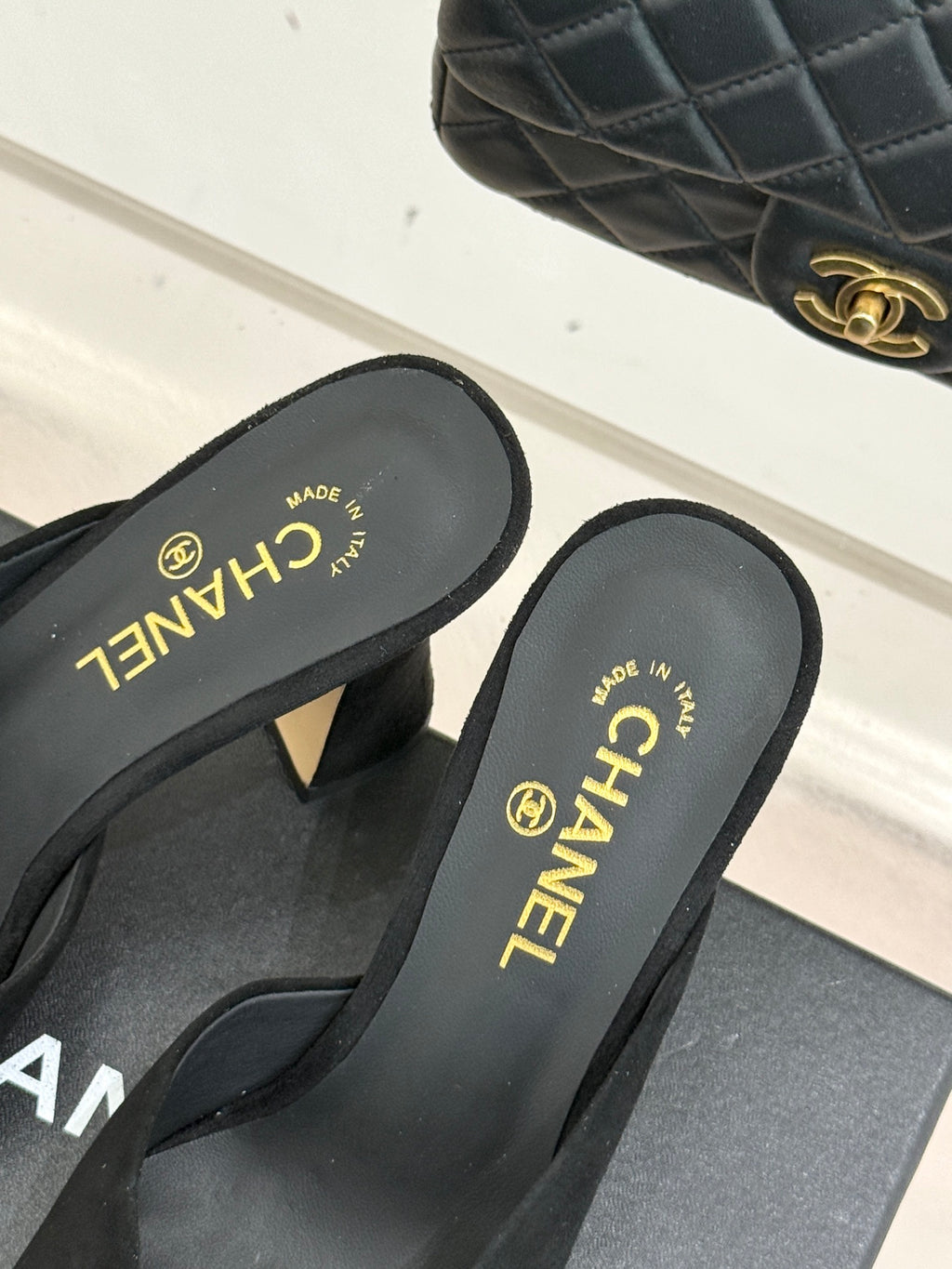 Black slide sandals with Chanel logo insoles and heeled profile