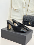 Black heeled slide sandals with gold logo on the strap and glossy square toe caps