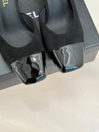 Close-up of black heeled mule sandals with silver patent-style toe caps