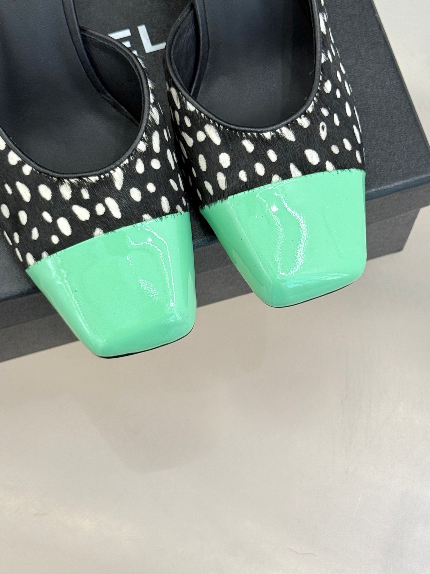 Front close-up of mule heels: black with white spots and mint green toe