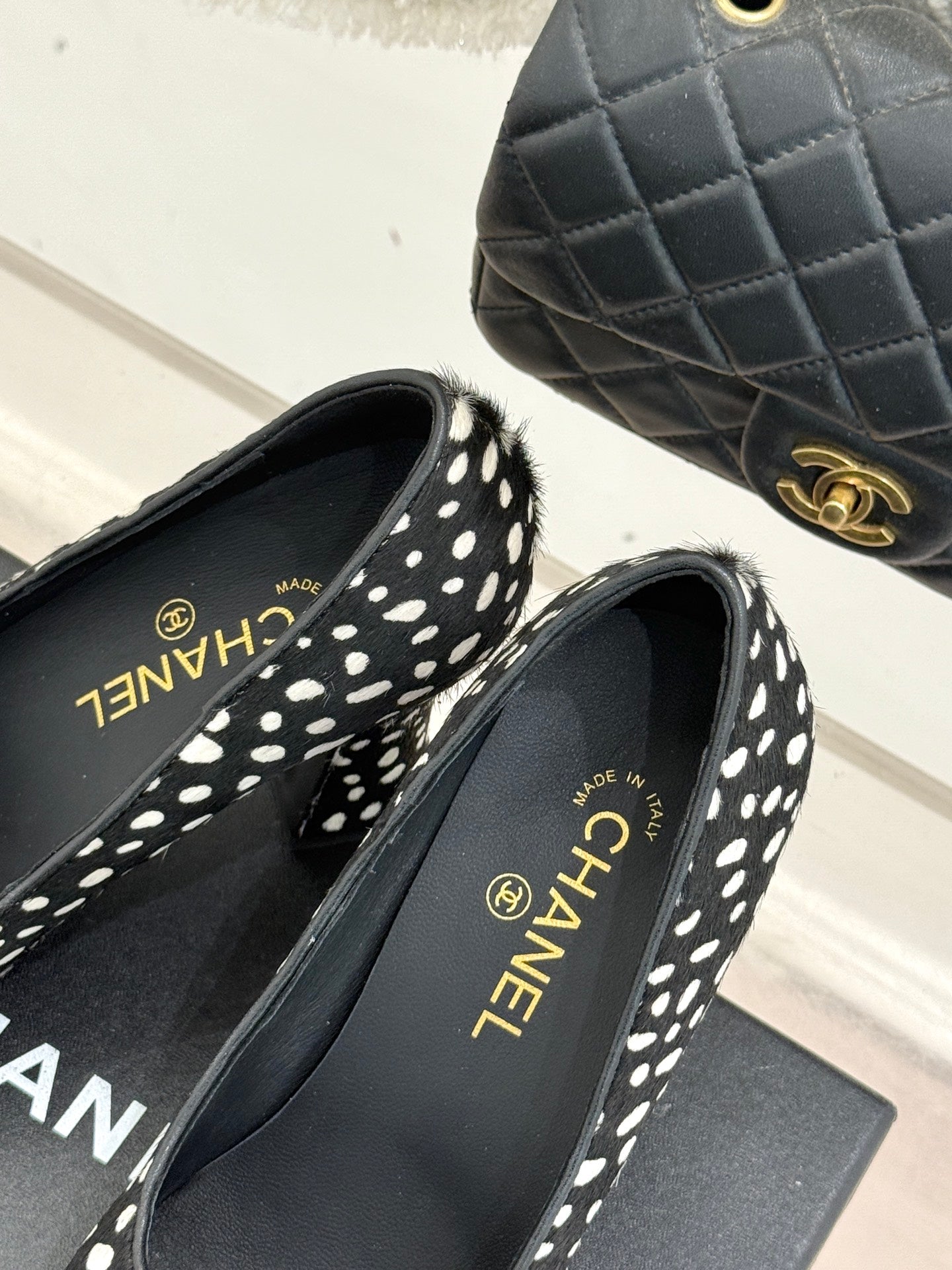 Polka-dot black pumps with red toe cap and CHANEL insole text, close-up.