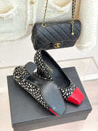 Polka-dot black pumps with red glossy toe cap on black shoebox, angled view.