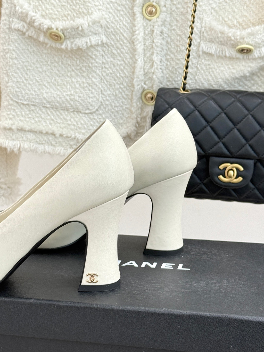 White mid-heel shoes with glossy black toe panels and gold logo on box