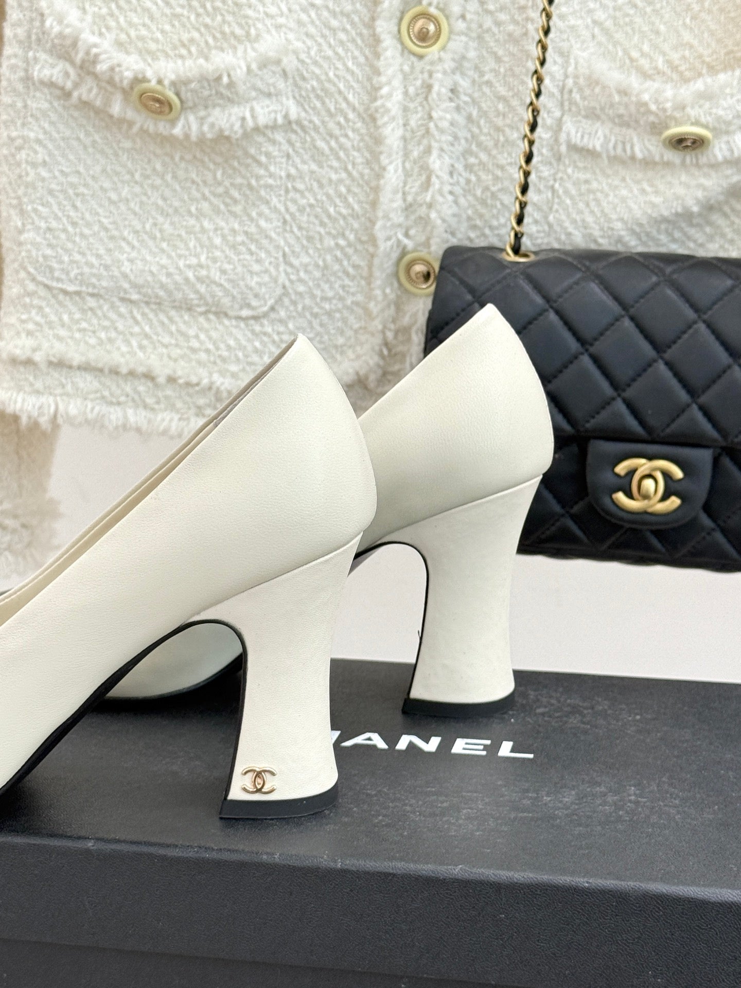 White mid-heel shoes with glossy black toe panels and gold logo on box