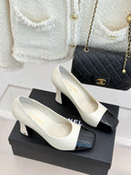 Pair of white and black heeled shoes with glossy black toe and strap