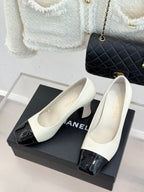 White heeled court shoes with glossy black toe cap and bow detail
