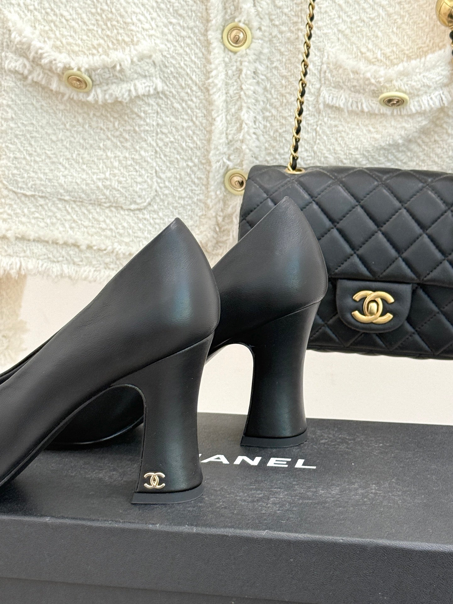 Black heeled pumps with block heels and patent toe detail, shown next to bag