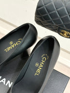 Black leather pumps with glossy patent toe; Chanel text on insoles