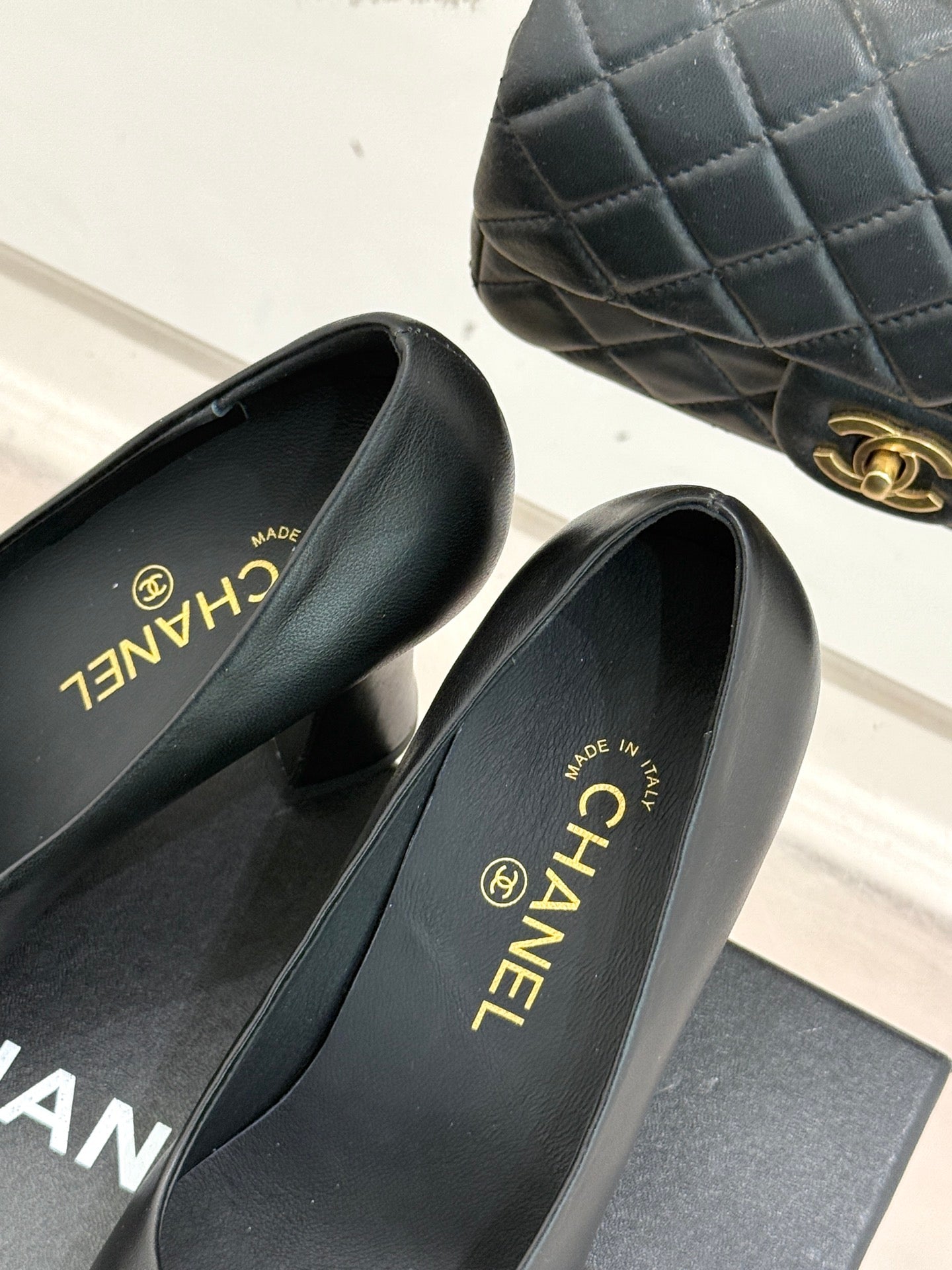 Black leather pumps with glossy patent toe; Chanel text on insoles