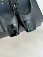 Close-up of black patent-toe pumps with block heel and glossy finish