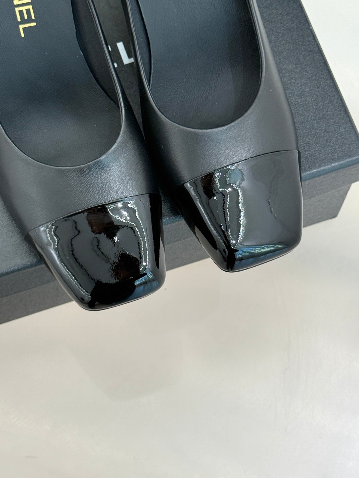 Close-up of black patent-toe pumps with block heel and glossy finish