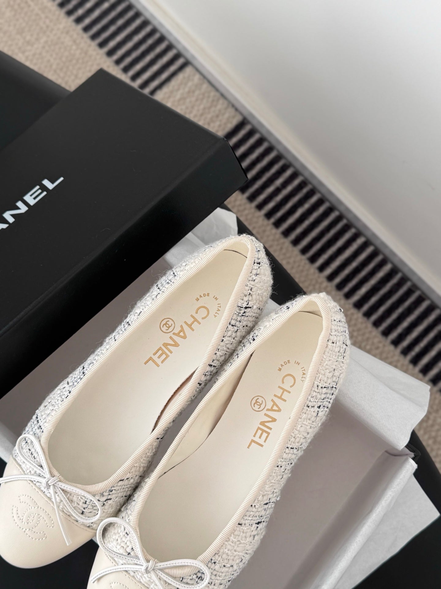 Close-up of cream tweed ballet flats with bow ties and printed insoles