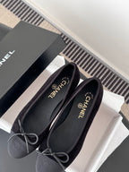 Dark lace-up ballet flats with bow ties beside CHANEL shoe box