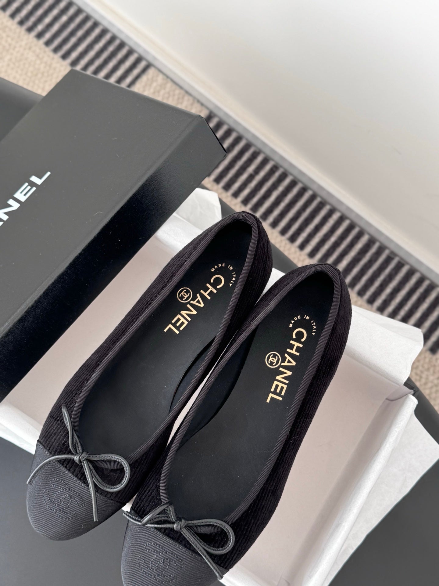 Dark lace-up ballet flats with bow ties beside CHANEL shoe box