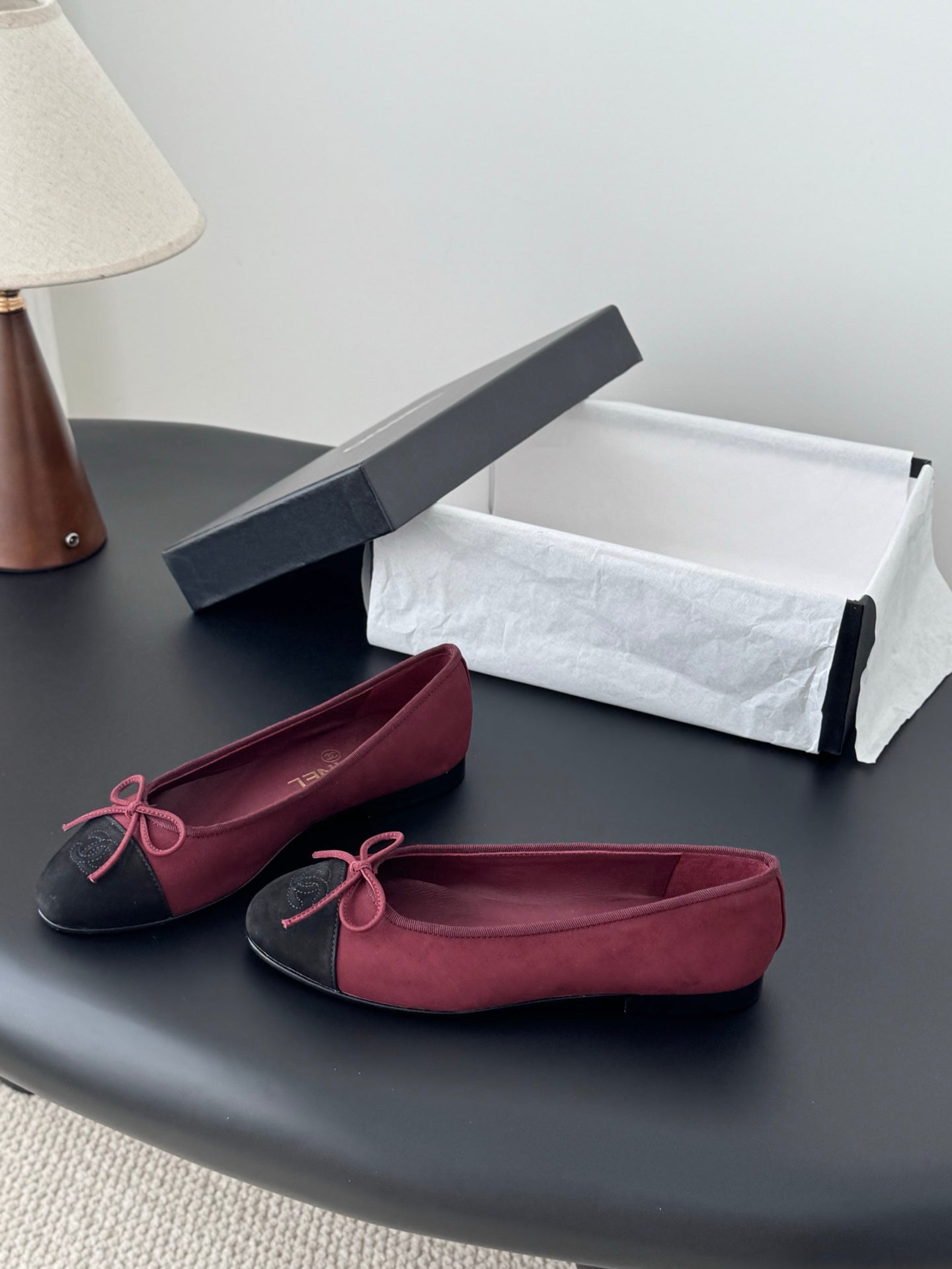 Chanel ballet flats in burgundy with black toe cap and pink bow, shown with shoe box