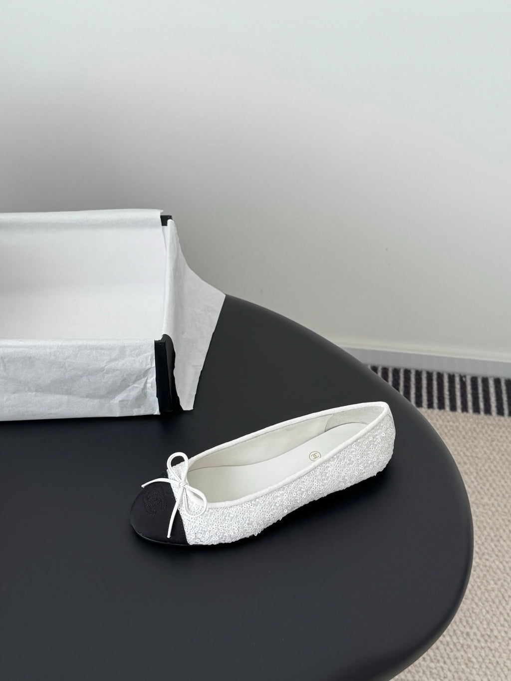 Two-tone ballet flat with white textured upper and bow-tied lace front, dark toe