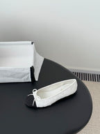 Two-tone ballet flat with white textured upper and bow-tied lace front, dark toe