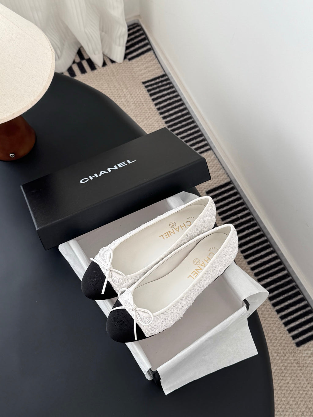 Two-tone ballet flats with white textured uppers, bow laces, and dark toe caps