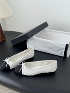 Two-tone ballet flats with textured white uppers, dark sides, and bow-tied lace detail