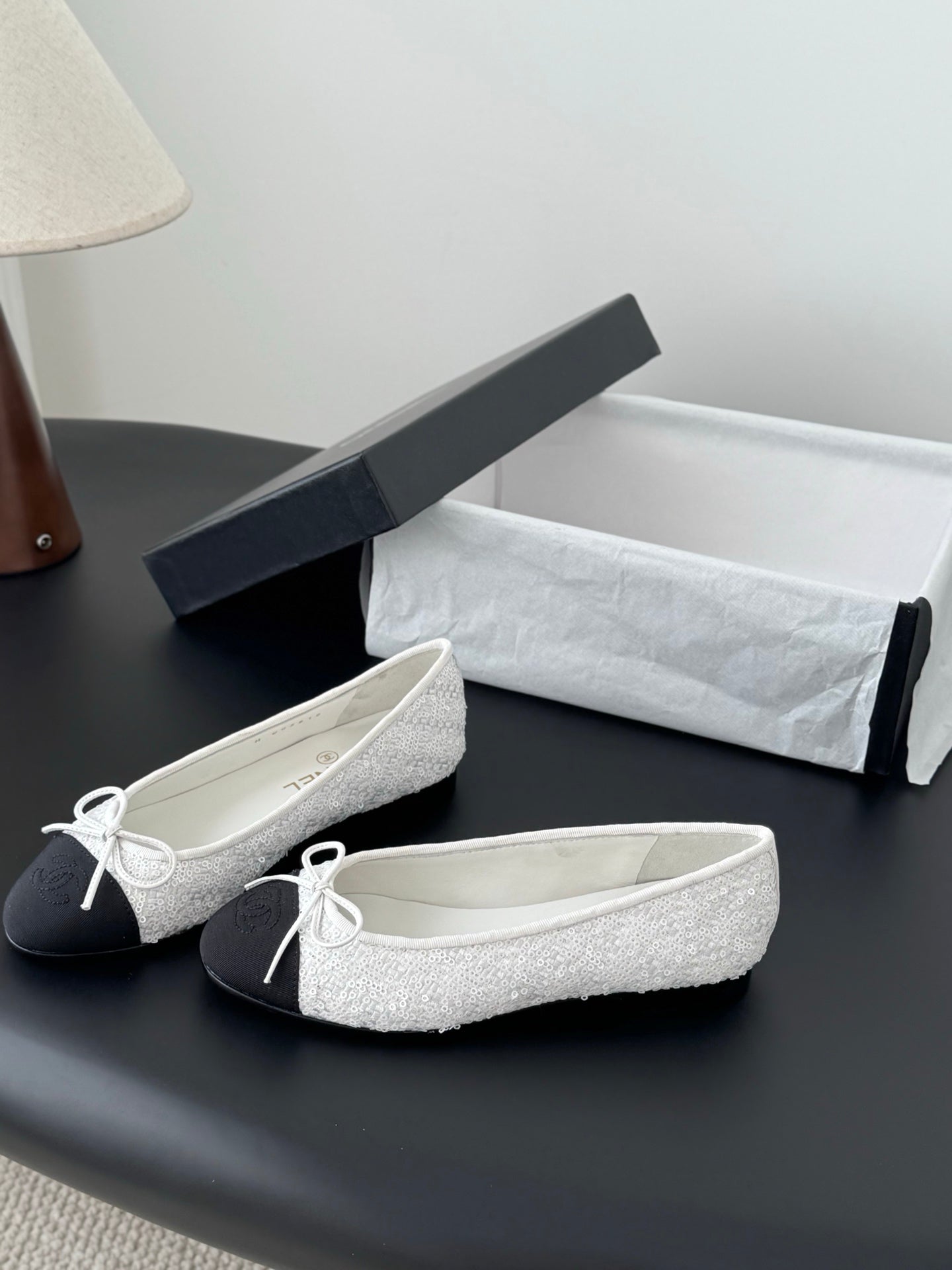 Two-tone ballet flats with textured white uppers, dark sides, and bow-tied lace detail