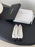 Two-tone ballet flats with white textured uppers and dark toe caps, tied bow laces