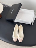 Pair of pale pink ballet flats with white laces and bow detail on toe.