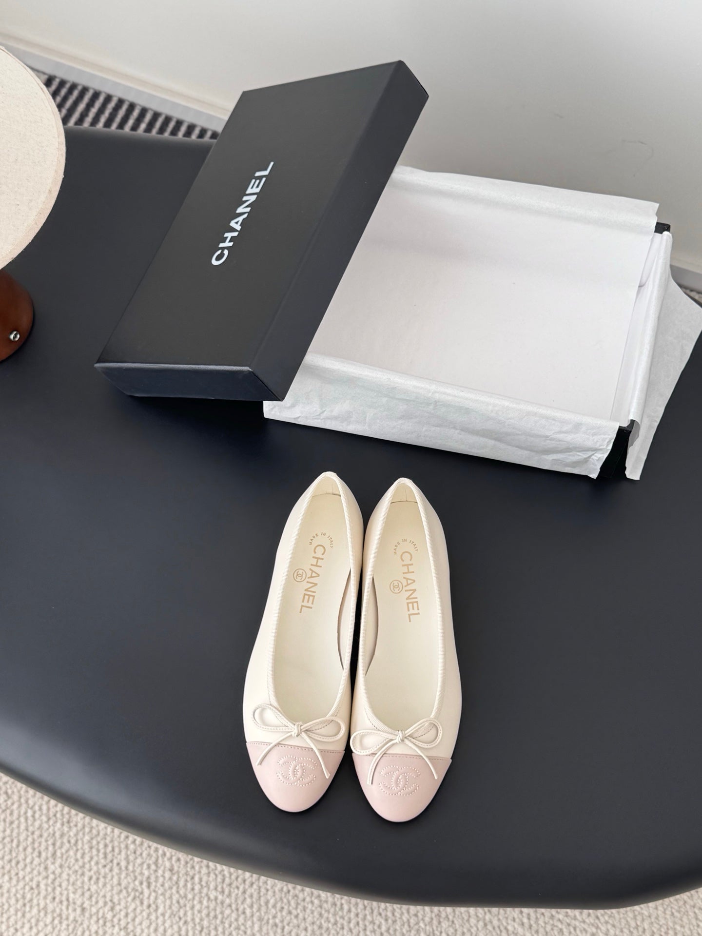 Pair of pale pink ballet flats with white laces and bow detail on toe.