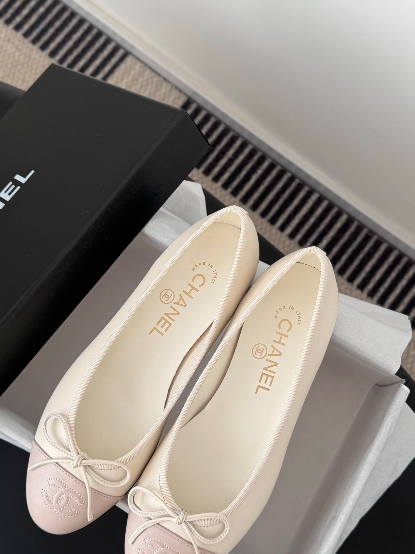 Pair of ballet flats with pale pink toe sections and white laces, close-up angle.
