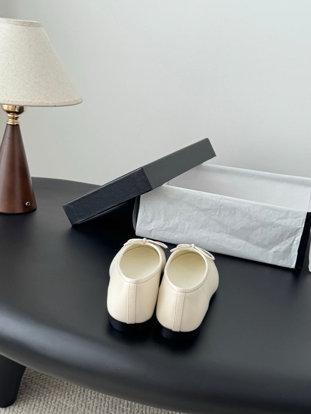 Back view of white ballet flats with ankle openings and tied bow detail.