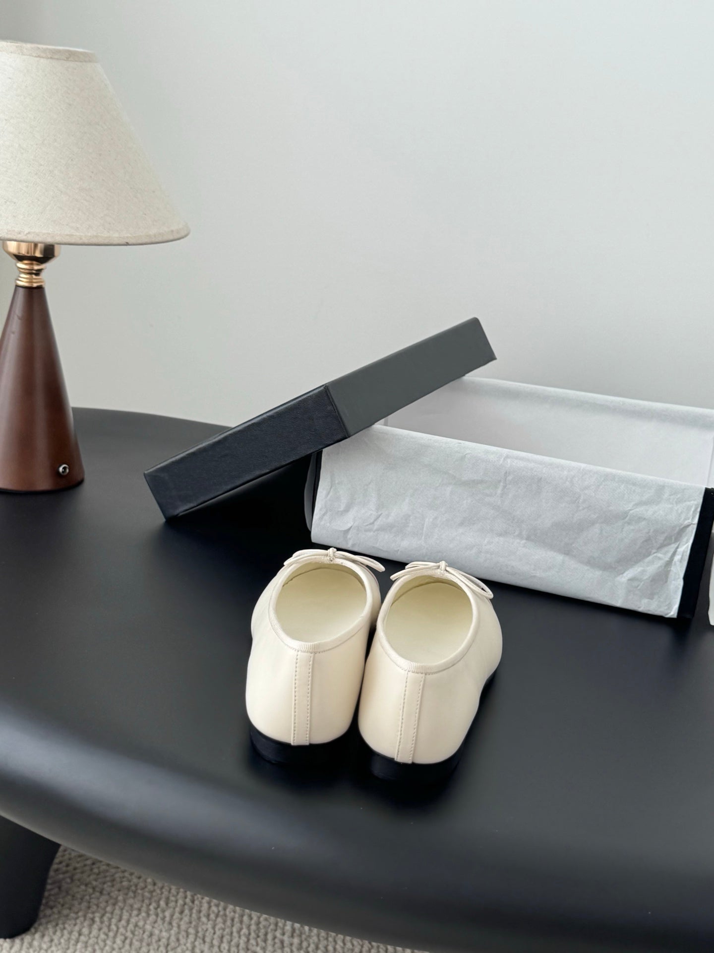 Back view of white ballet flats with ankle openings and tied bow detail.
