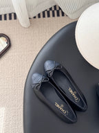 Pair of dark ballet flats with ribbon bow and CHANEL logo on insoles