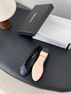 Dark CHANEL ballet flats with ribbon bow and rounded toe, showing light insole