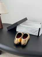 Gold metallic ballet flats with round toe and bow ties on display surface