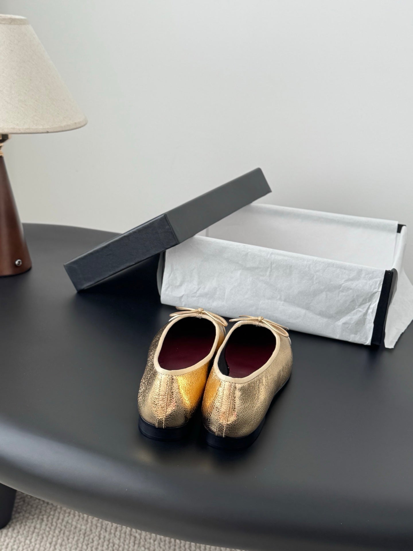 Gold metallic ballet flats with round toe and bow ties on display surface