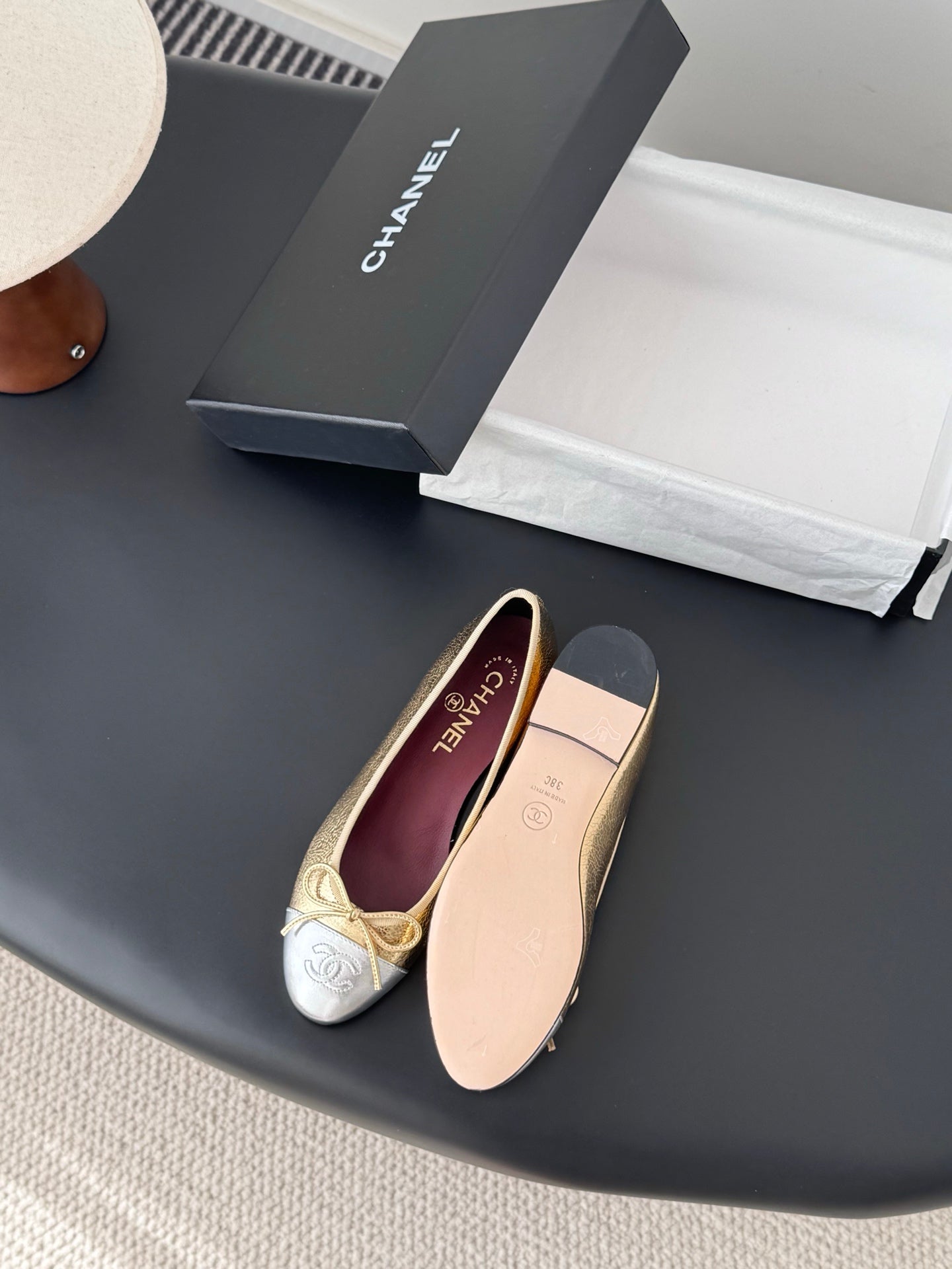 Gold-and-cream ballet flats with bow ties and round toe, laid on surface