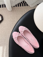 Pink ballet flats with bow laces, rounded toe, suede-like texture