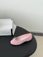 Pink ballet flat with bow laces and textured fabric upper, rounded toe
