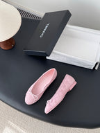 Pair of pink ballet flats with bow tie detailing and rounded toe