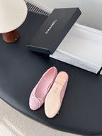 Pink ballet flats with bow laces, one showing tan outsole