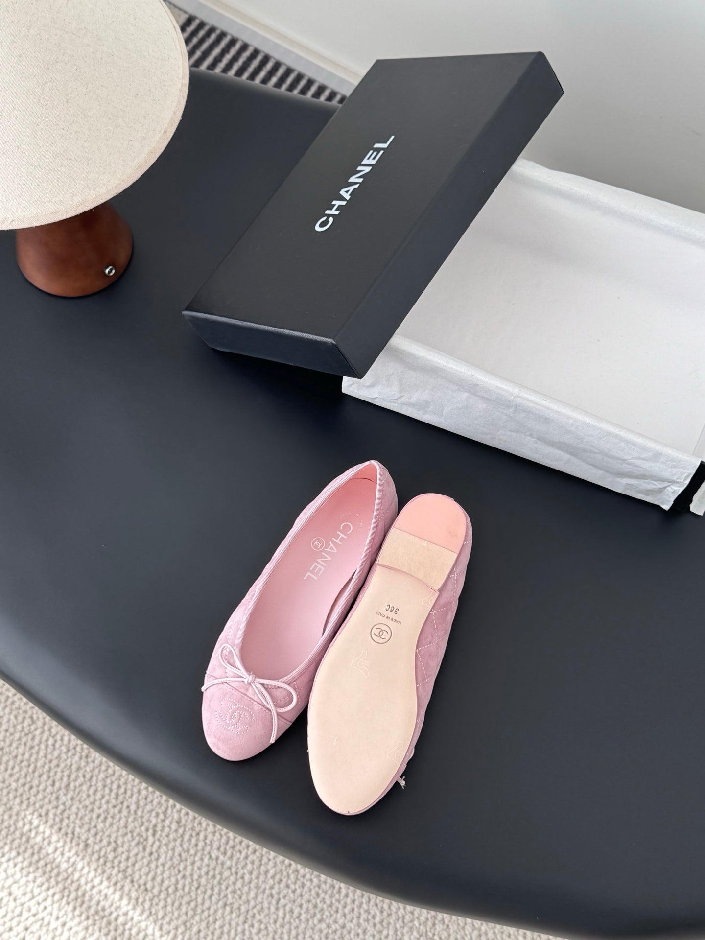 Pink ballet flats with bow laces, one showing tan outsole