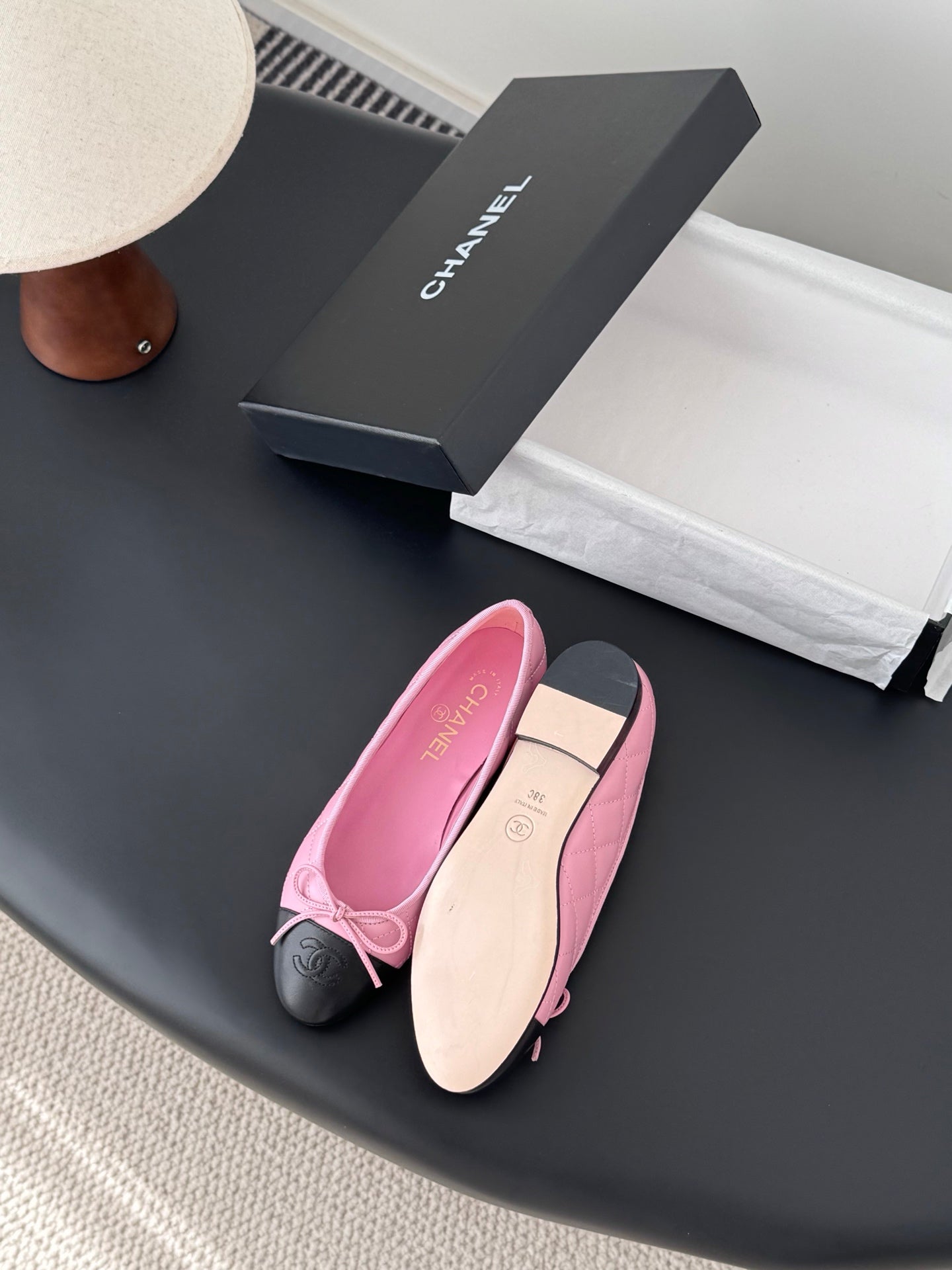 Chanel pink ballet flats with bow and black toe caps beside beige soles