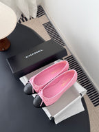 Chanel pink ballet flats with bow and black toe caps next to black logo box